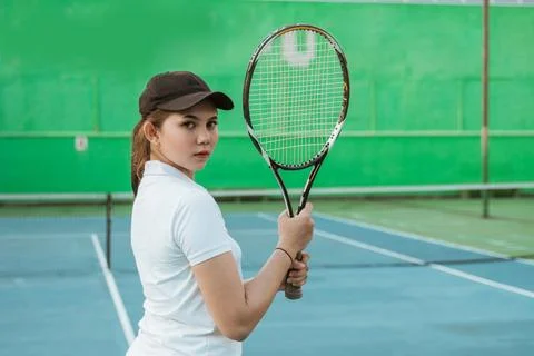 Tennis athlete looking back while holding racket on tennis court Stock-Fotos