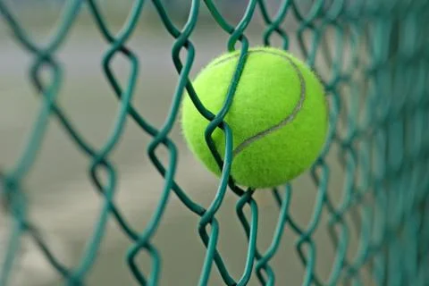 Tennis ball in the chainlink behind court Stock Photos