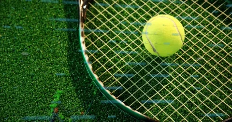 Tennis ball resting on racket strings highlighting fuzzy texture against vibrant Stock Footage 328155222