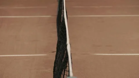 A tennis net is set up with a ball resting on the clay court surface, ready for Stock Footage 285605671