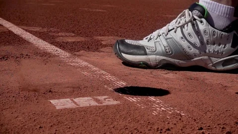 A tennis player bouncing the ball on a clay court, preparing to serve. Stock Footage 75705100