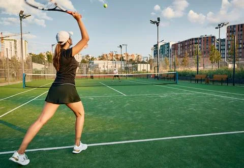 Tennis player serves ball while playing match with her male partner on a gr.. Fotos Stock