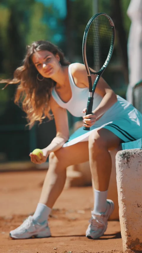 Tennis player smiling while holding a tennis ball on a clay court in warm Stock Footage 338243377