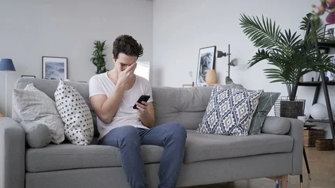 Tense Frustrated Man Reaction, while Using Smartphone Video stock 88310712