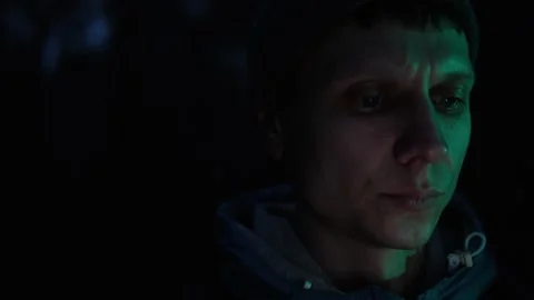 A tense man in the dark forest at night, scanning his surroundings before Stock Footage 302350474