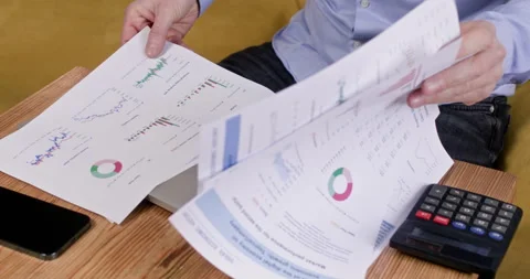 Tense man reviews cryptocurrency analytics documents at table Stockbeeldmateriaal 304489863