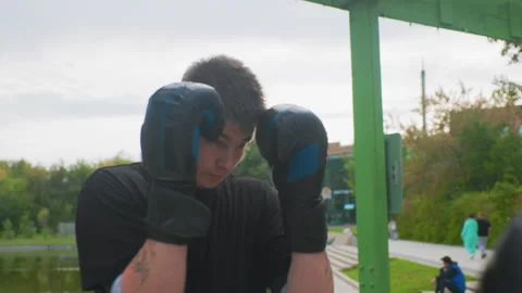Tense student trains with protective gear outdoors, Athletic individual Stock Footage 330957181
