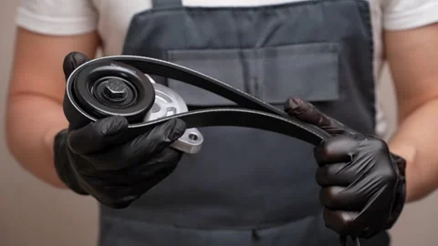 Tensioner roller and poly V-belt in hands of car mechanic. Concept of auto parts Stock Footage 276526140