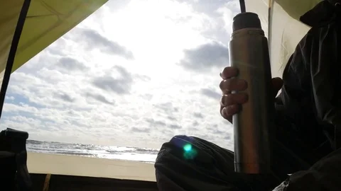Tent on the beach. 4k. view from the tent on the sea. a male tourist is sitting Stock Footage 82147977