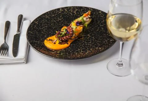 Tentacles of an octopus on a mango puree, restaurant serving of a dish Stock Photos