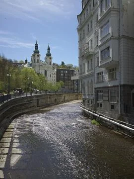 The Tepla river running between spa buildings toward a church in Karlovy Vary, C Stock Photos
