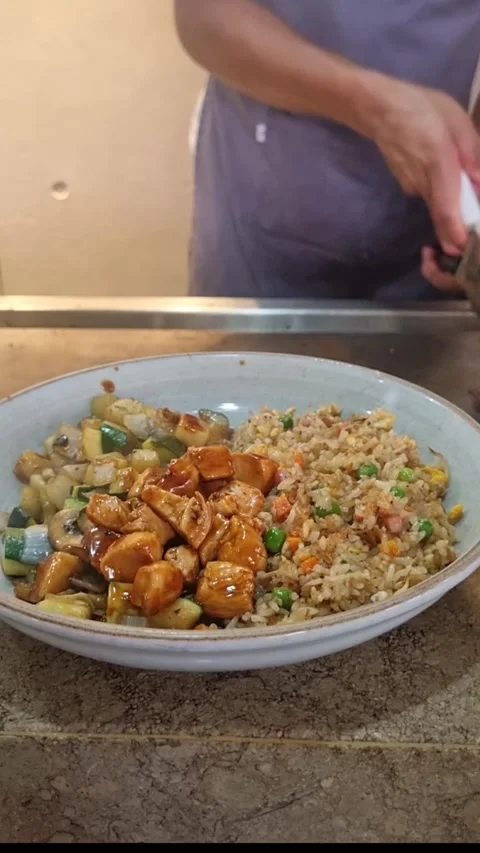 Teppanyaki chef serving chicken and steak hibachi dish Stock Footage 346559036