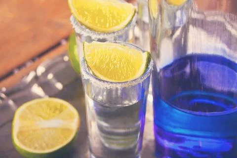 Tequila shot with lime and sea salt and blue bottle on tray 库存照片