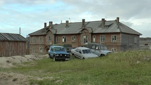 Teriberka, Russia. Old dilapidated wooden house and cars. Editorial use. Stock Footage