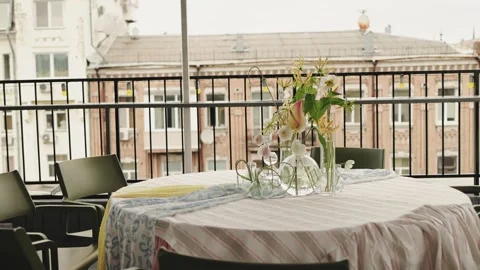 Terrace table with glass vases patterned tablecloth wrought iron railing brick Stock Footage 325843556