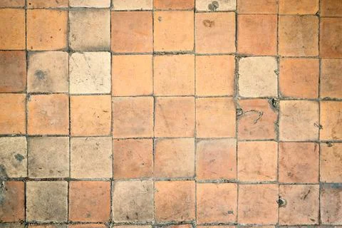 Terracotta floor features rustic square clay tiles. Weathered vintage texture Stock Photos