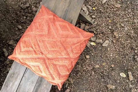 Terracotta patterned outdoor cushion placed on wooden garden bench Stock Photos