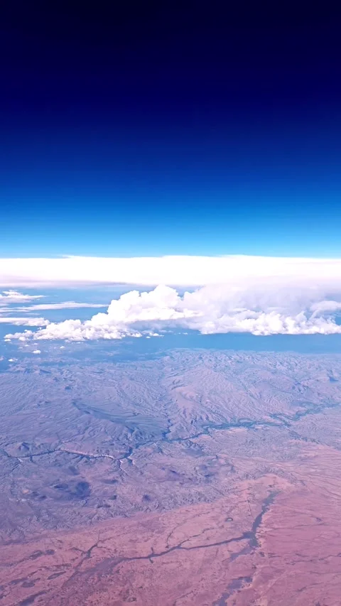 Terrain, Sky, and Clouds from POV of a Plane Passenger Stock Footage 317893558