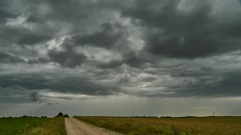 A terrible rain cloud hangs over an agricultural field and a dirt road. Hurri Foto stock