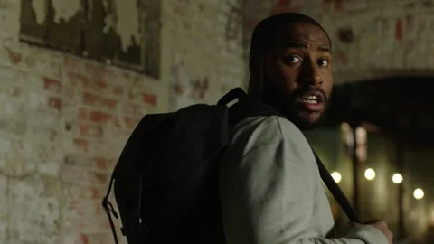 Terrified man with backpack stops for breath and looks behind before running in Stock-Footage 199455446