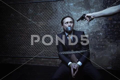 Terrified pathetic man being threatened with a gun Stock Photos