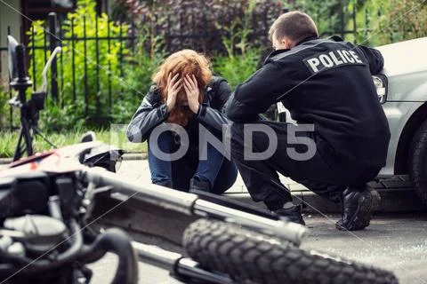Terrified victim of a traffic collision of motorcycle with a car and policema Stock Photos
