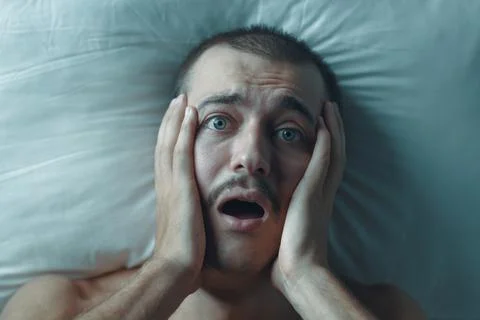 Terrified Young Man Screaming in Bed During a Nightmare Stock Photos