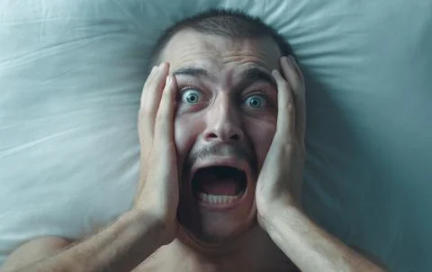 Terrified Young Man Screaming in Bed During a Nightmare Stock Photos