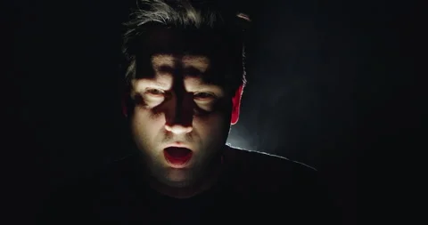 A terrifying face of a middle-aged zombie man, illuminated from below with long Stock Footage 294900076