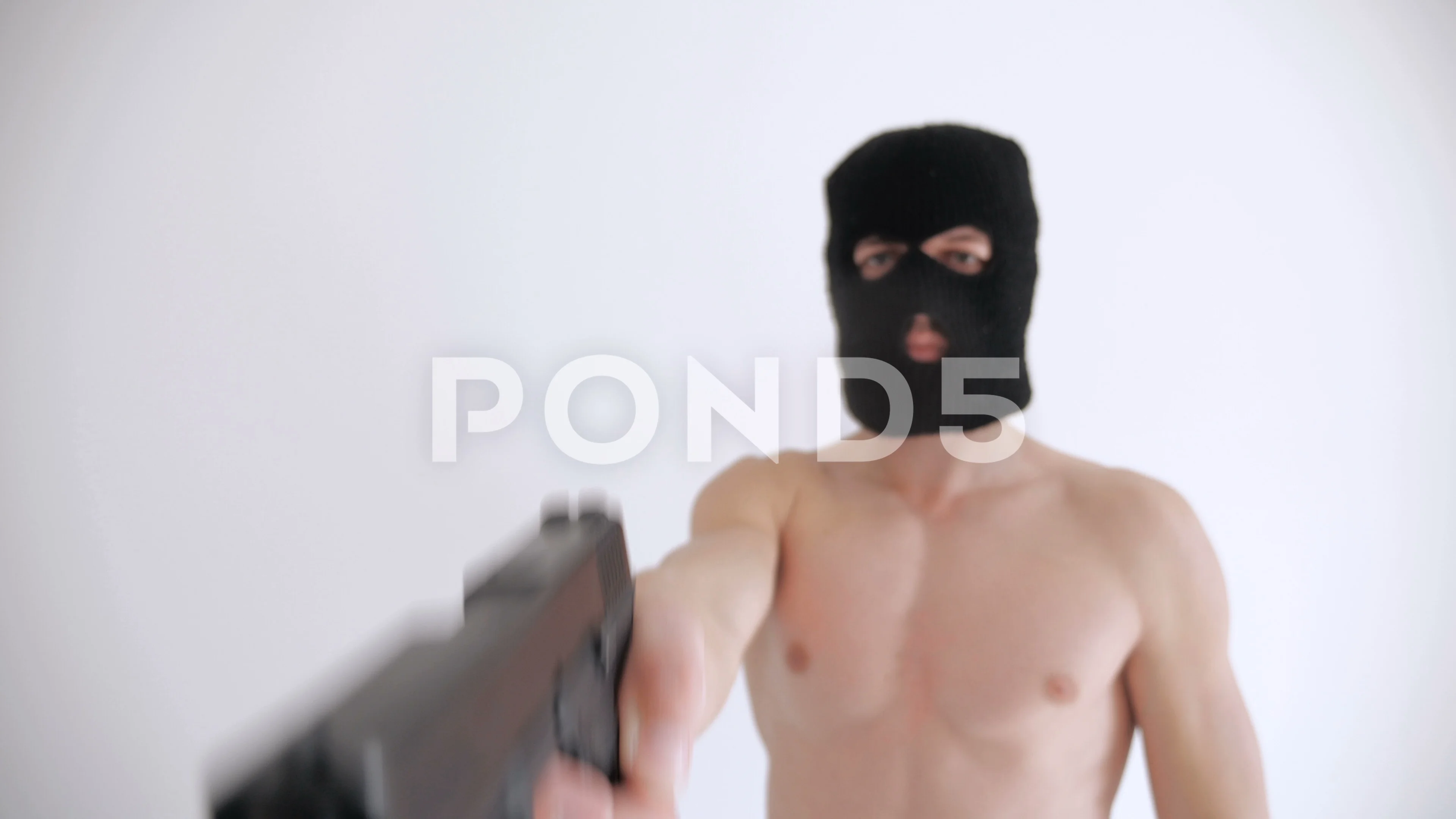 Terrorist with a naked torso in balaclava aims his gun on white background