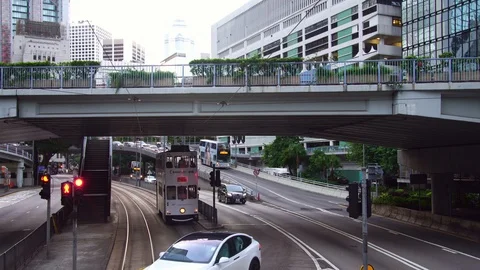 Tesla electric car passing in front of double-decker city tram bus in downtown  Stock Footage 88759231
