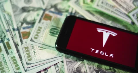 Tesla Logo on iphone surrounded by $100 Bills. Tesla Profits Layout. Stock Footage 169009162