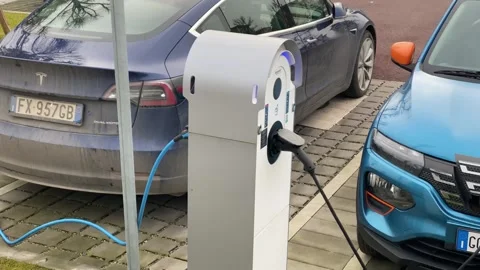 Tesla model 3 and Dacia Spring charging in Cremona, Italy Stock Footage 302584063
