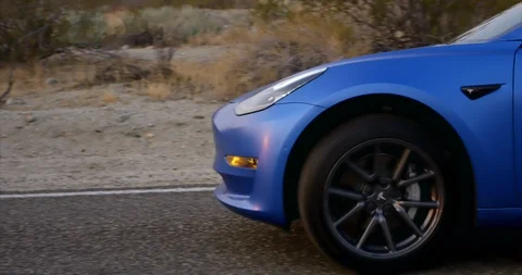 Tesla model 3 car on desert highway - slowly driving by Vidéo 105581377