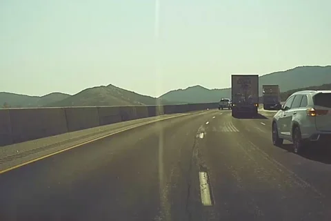 A Tesla Model 3 dash cam records a car nearly crashing into a semi truck. Stock Footage 157793394
