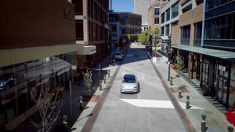 Tesla Model 3 drives between buildings and under drone. Stock-Footage 93419923