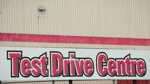 Test drive centre writing caption text horizontal sign on fence with beige red Stock Footage 249759550