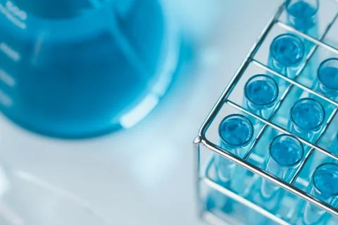 Test tubes and erlenmeyer flask filled with blue sample chemicals in chemis.. Stock Photos