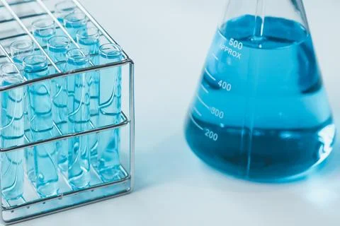 Test tubes and erlenmeyer flask filled with blue sample chemicals in chemis.. Stock Photos