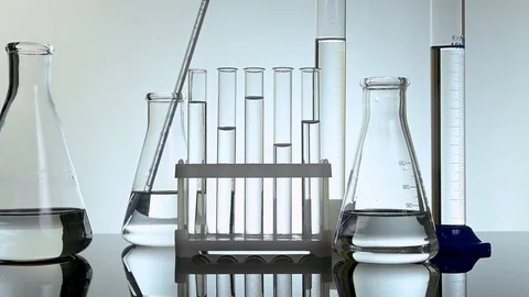 Test tubes and flasks stand with clear liquids on a table in a laboratory Video stock 121635051