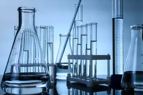 Test tubes and flasks stand with clear liquids on a table in a laboratory Stock Photos