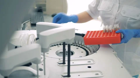 Test tubes are getting inserted into a biochemical analyzer by a lab worker Video stock 93734253