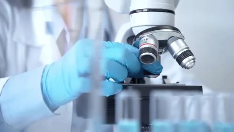 Test tubes with a blurred scientist in a lab coat in the background Stock-Fotos
