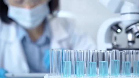 Test tubes with a blurred scientist in a lab coat in the background Stock-Fotos