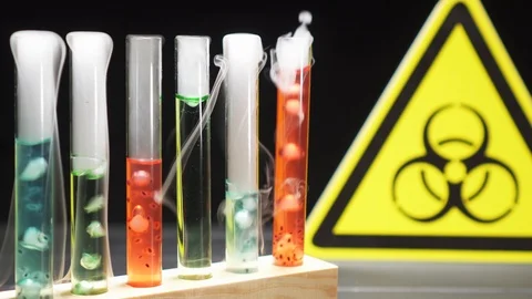 Test tubes with boiling multi-colored liquid on the background of the biohazard Stock Footage 123538905