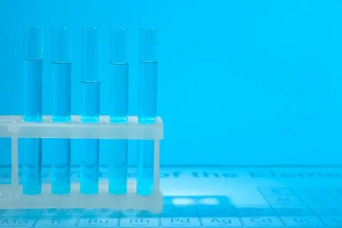 Test tubes on periodic table of elements, toned in light blue. Space for text Stock Photos