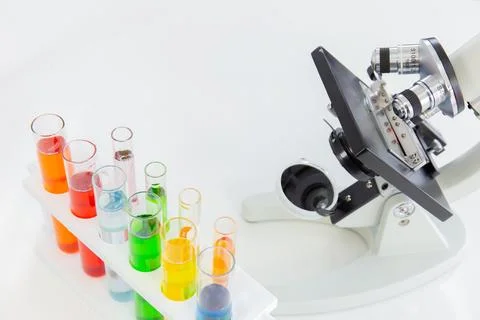 Test tubes in a stand and a microscope on a white table Stock-Fotos