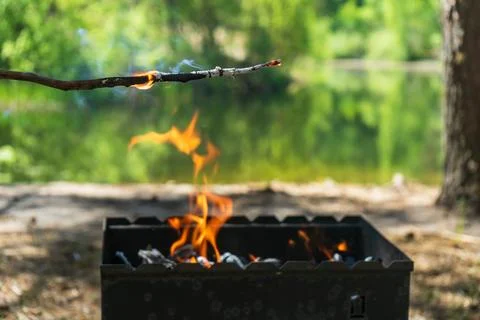 Testing fire for charcoal barbecue grill beside peaceful lake Stockfoto's