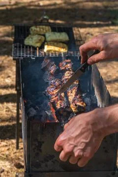 Testing grilled meat readiness during outdoor barbecue with vegetables on gri Stock-Fotos