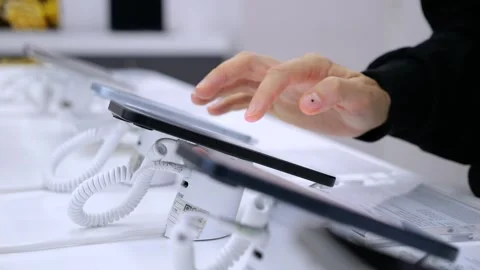 Testing phones in store. Close-up: hand checking functions of phones on stand in Stock Footage 270483315